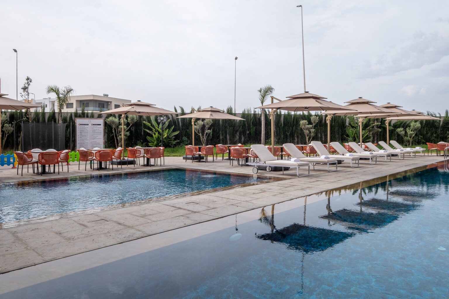 La piscine extérieure, ses parasols et la façade de l'hôtel